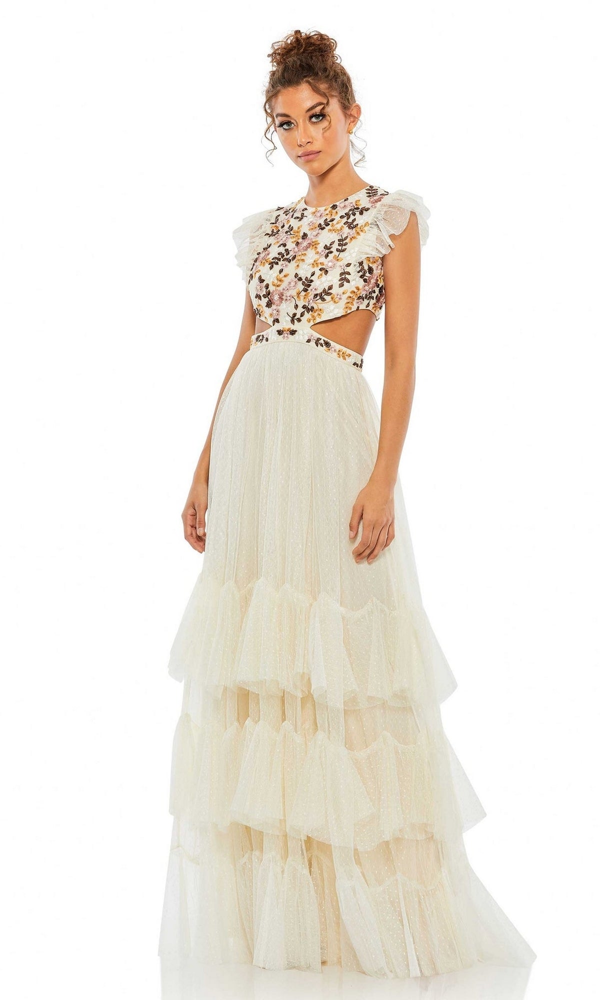 Woman standing against a white background wearing the Long Formal Dress 35106 by Mac Duggal, featuring a sleeveless, floral embroidered top with ruffle details and a long, tiered cream tulle skirt.